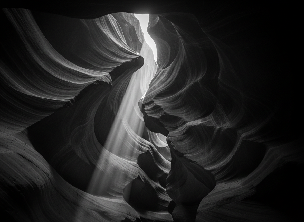 A dramatic black and white photo of a canyon similar in style and composition to Upper Antelope Canyon, featuring sweeping rock formations and high contrast lighting, suitable as a hero image.
